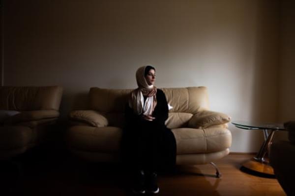 A woman sits on a couch in a dimly lit room